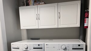 A laundry area with two white LG front-loading washing machines, a white cabinet above, and a fire extinguisher on the wall. - Bright Condo With Views & Easy Access to CDA River.  Minutes From Gondola! (Kellogg)