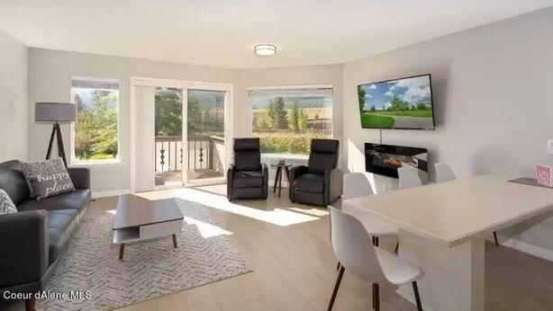 A modern living room with a sofa, coffee table, chairs, a dining table, and a TV. - Bright Condo With Views & Easy Access to CDA River.  Minutes From Gondola! (Kellogg)