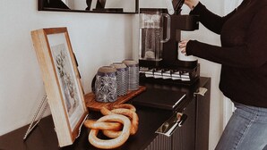 A person using a coffee machine in a room with a mirror, a framed picture, and decorative items on a counter. - Escape to Shenandoah River, Hot Tub after a Hike!  (Front Royal)