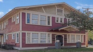 A two-story house with a red exterior and white trim, featuring a front porch and a garage.