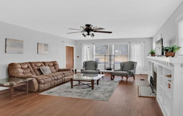 A living room with a brown leather sofa, a gray armchair, a coffee table, and a fireplace with a mantel.
