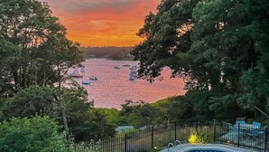 Una piscina con vista su un fiume e sulle imbarcazioni al tramonto.