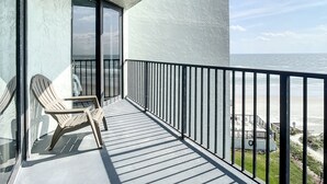En balkong med utsikt över havet, en stol och ett bord.