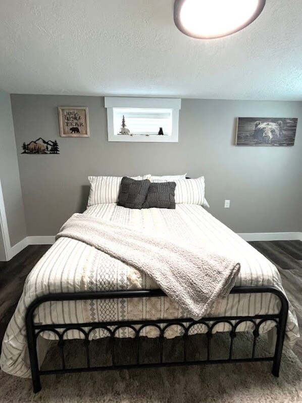 A bedroom with a bed, a window with a view, and wall decorations. - Southfork home sleeps 12 private setting w/ hot tub (Ririe)