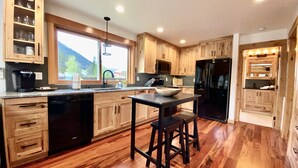 Una cocina moderna con armarios de madera, un refrigerador negro y un ventanal con vistas al exterior.