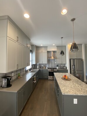 A modern kitchen with grey cabinets, stainless steel appliances, and a granite countertop.