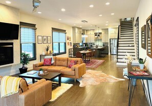 A modern living room with a sofa, coffee table, and a dining area with chairs.
