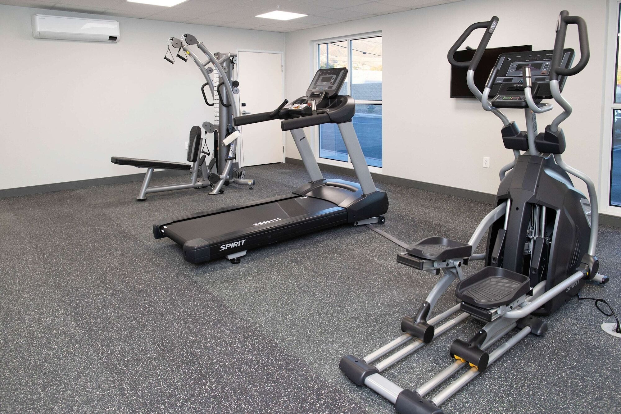Un gimnasio con cinta de correr, elíptica y máquinas de pesas.