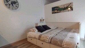 Una camera da letto con un letto, una sveglia a forma di mappamondo, un quadro e un pavimento in legno.