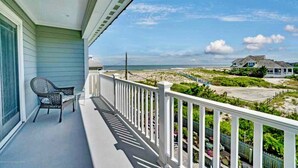 A balcony with a chair, a view of the beach, and a house in the background. - Dream Beach House packed with Style, Comfort, and Convenience (Mantoloking)