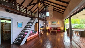 Un amplio espacio de estar con una escalera de madera, un conjunto de sofás y una mesa de comedor.