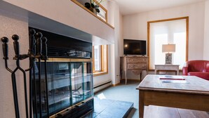 Een moderne woonkamer met een open haard, televisie en zithoek.