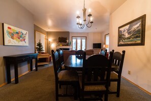 A dining area with a wooden table and chairs, a chandelier, a map on the wall, and a painting.