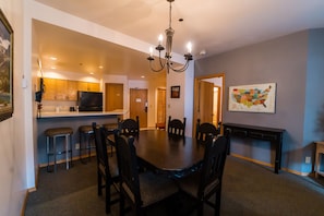 A dining area with a large table and chairs, a chandelier, and a map on the wall.