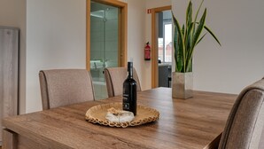 A wooden dining table with a bottle of wine, a placemat, and a potted plant. - Tamariz Sea View, a Home in Madeira (Caniço)