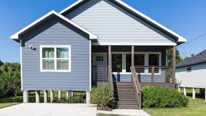 A single-story house with a gabled roof, a front porch with a wooden railing, and a small staircase leading to the entrance. - 3BR Comfy Bungalow 1747! Medical Center, Stadiums! ⭐️⭐️⭐️⭐️⭐️ (Houston)