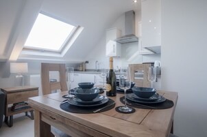 Eine moderne Küche mit Oberlichter, einem Holzespeisetisch, der mit Geschirr gedeckt ist, und einer Weinflasche.