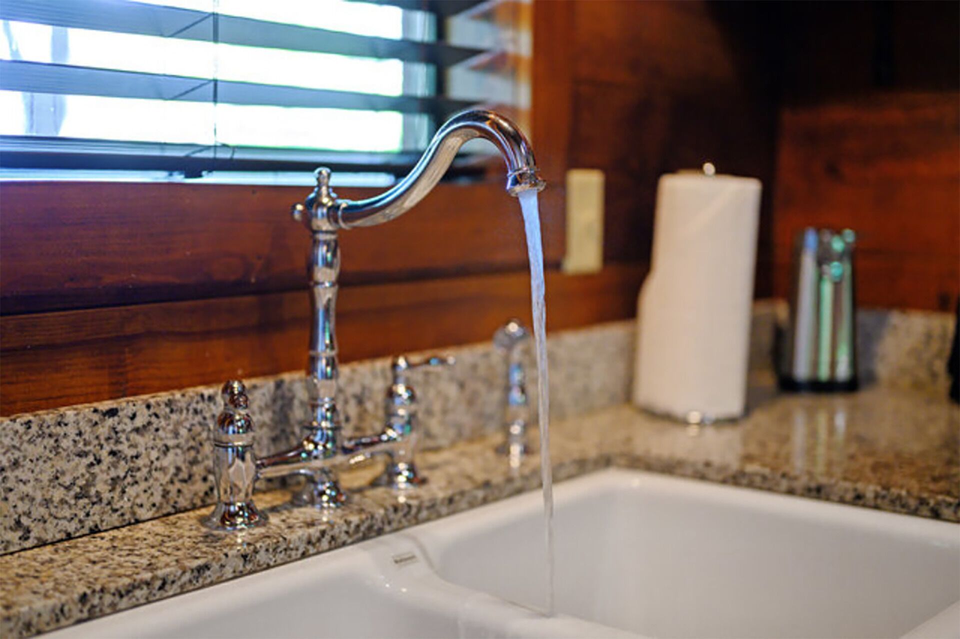 A bathroom sink with a running faucet and a candle on the counter.