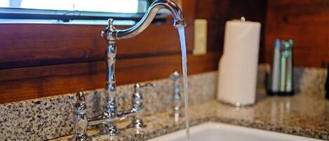 A bathroom sink with a running faucet and a candle on the counter.