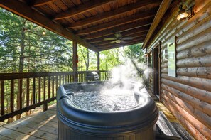 Un bain à remous sur une terrasse en bois, avec un chalet en bois en arrière-plan.