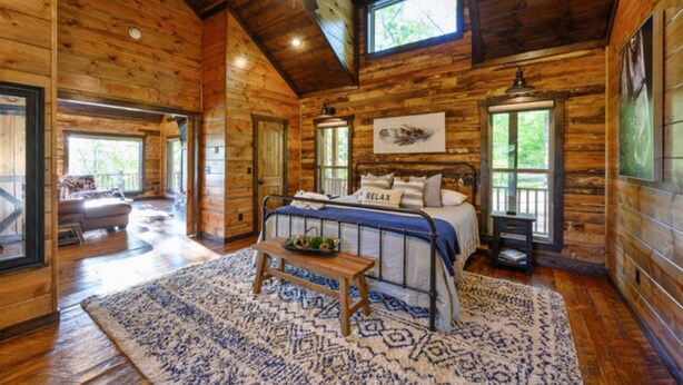A log cabin bedroom with a bed, a bench, a rug, and a ceiling fan. - Fireplaces, hot tub, romantic cabin perfect for a honeymoon or a getaway for two (Ringold)