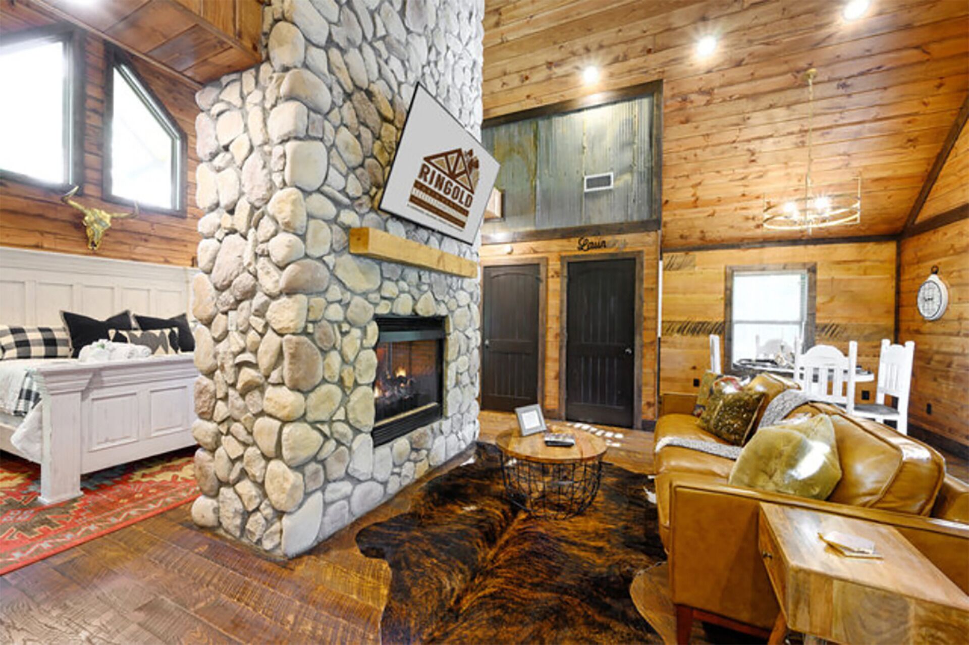 L’intérieur d’une cabane en rondins, avec une cheminée en pierre, des murs en bois et un coin salon confortable.