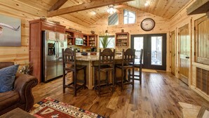 Ein Holzblockhaus-Innenraum mit Küche, Essbereich und Wohnzimmer mit einer Couch.
