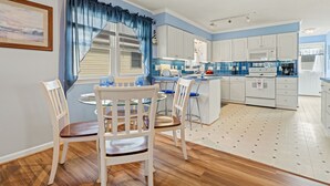 Een moderne keuken met witte kasten, een centraal eiland en blauwe accenten.