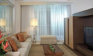 Relax in comfort with a sofa set, flat-screen TV, and large mirror.