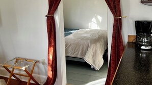 Een kamer met een bed, een koffiezetapparaat en een houten stoel.
