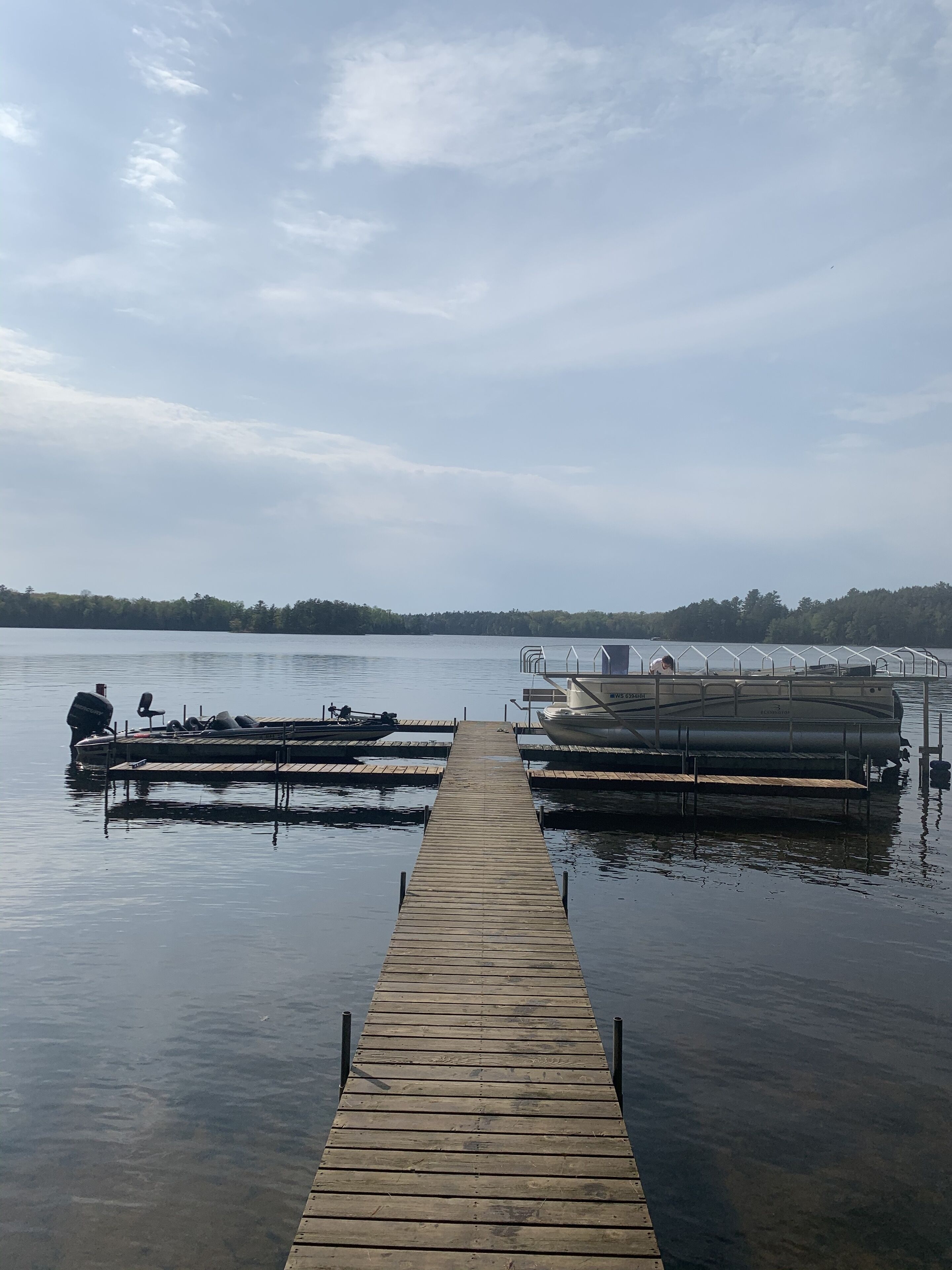 A wooden pier extending into calm water, with boats docked on either side.