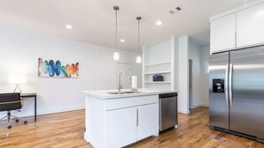 A modern kitchen with a central island, stainless steel appliances, and wooden flooring. - 3BR Cozy Bungalow 1749! Medical Center, Stadiums! (Houston)