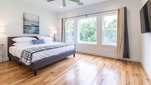 A bedroom with a bed, a ceiling fan, a window with curtains, and a painting on the wall. - 3BR Cozy Bungalow 1749! Medical Center, Stadiums! (Houston)