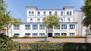 Ein mehrgeschossiges Gebäude namens Villa Patricia mit einer symmetrischen Fassade, großen Fenstern und einem zentralen Eingang.