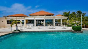 Un hotel con piscina, mobiliario exterior y un patio cubierto.