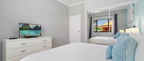 Une chambre à coucher avec un grand lit, une commode, une télévision et un miroir.