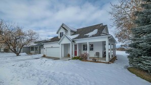 Et toetagers hus med en overdækket veranda og garage.