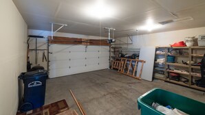 En garage med en hvid dør, en arbejdsbord og diverse værktøj og udstyr.