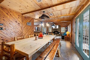 A rustic wooden interior with a long dining table, benches, a stone fireplace, and a large window. - Game Room with pool table and ping pong, hot tub, less than a mile from lake (Ringold)