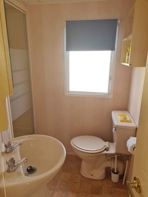 Ein kleines, kompaktes Badezimmer mit Toilette, Waschbecken und Fenster.
