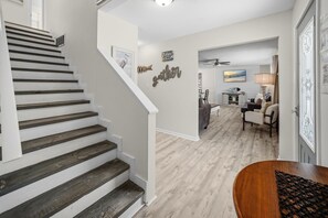 A staircase with white railings and wooden steps leading to a living area with a dining table and chairs.