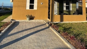 Un edificio de dos pisos con fachada marrón, un pequeño porche delantero y un camino de entrada pavimentado.