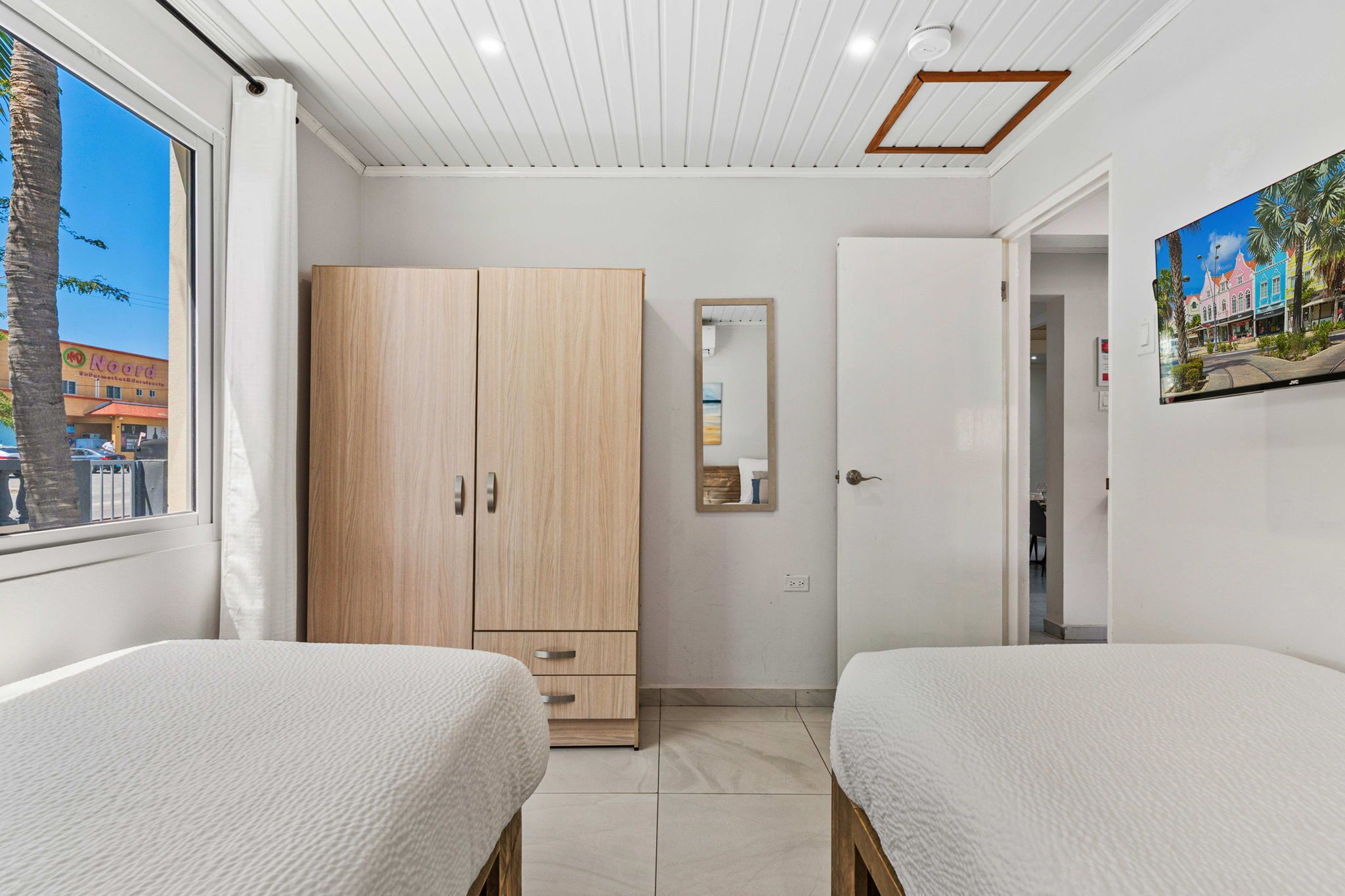 Un dormitorio con dos camas, un armario, un espejo y un cuadro en la pared.