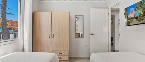 Un dormitorio con dos camas, un armario, un espejo y un cuadro en la pared.
