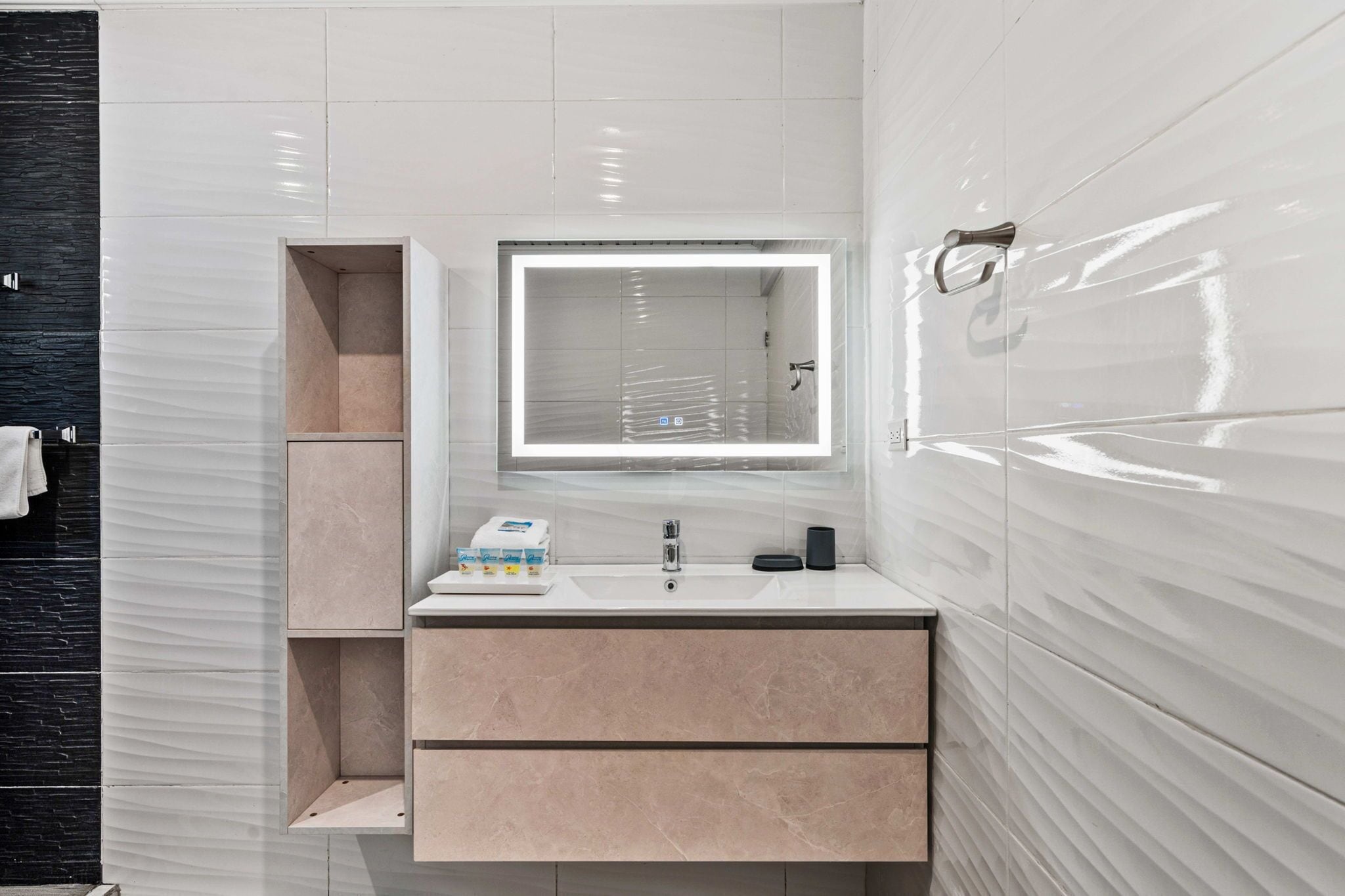 Une salle de bain moderne avec un grand miroir, un lavabo et un meuble-lavabo doté de tiroirs de rangement.