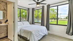 A bedroom with a bed, a ceiling fan, a large window with curtains, and a view of a green landscape. - Spacious Miami Getaway ~ 8 Mi to South Beach! (Miami)