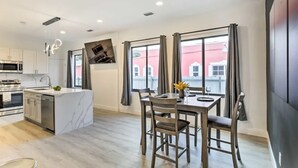 A modern kitchen with a central island, dining table with chairs, and large windows with curtains. - Spacious Miami Getaway ~ 8 Mi to South Beach! (Miami)