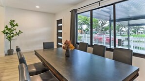 A conference room with a long table, chairs, a potted plant, and large windows with a view of a fenced area and trees. - Spacious Miami Getaway ~ 8 Mi to South Beach! (Miami)