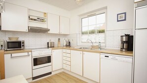 A modern kitchen with white cabinetry, a microwave, stove, oven, sink, and a coffee maker. - Vacation home Wiking - in a quiet location, beautiful vacation home with terrace and garden (Binz)