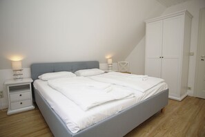 A bedroom with a bed, bedside tables, a wardrobe, and a lamp.
